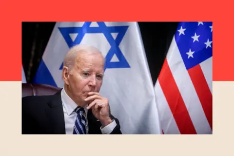 Getty Images US President Joe Biden with his hand to his face, as he sits in front of flags