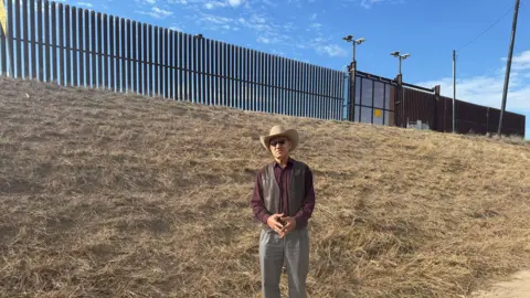 Bernd Debusmann Jr/BBC News Demesio Guerrero standing by the border wall in Hidalgo, Texas.